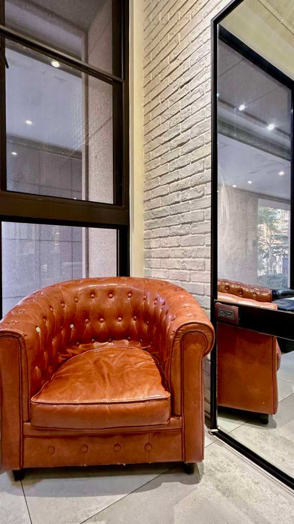 客人休息區｜柔軟皮革沙發與自然光交織的溫馨角落，營造舒適放鬆的等待空間